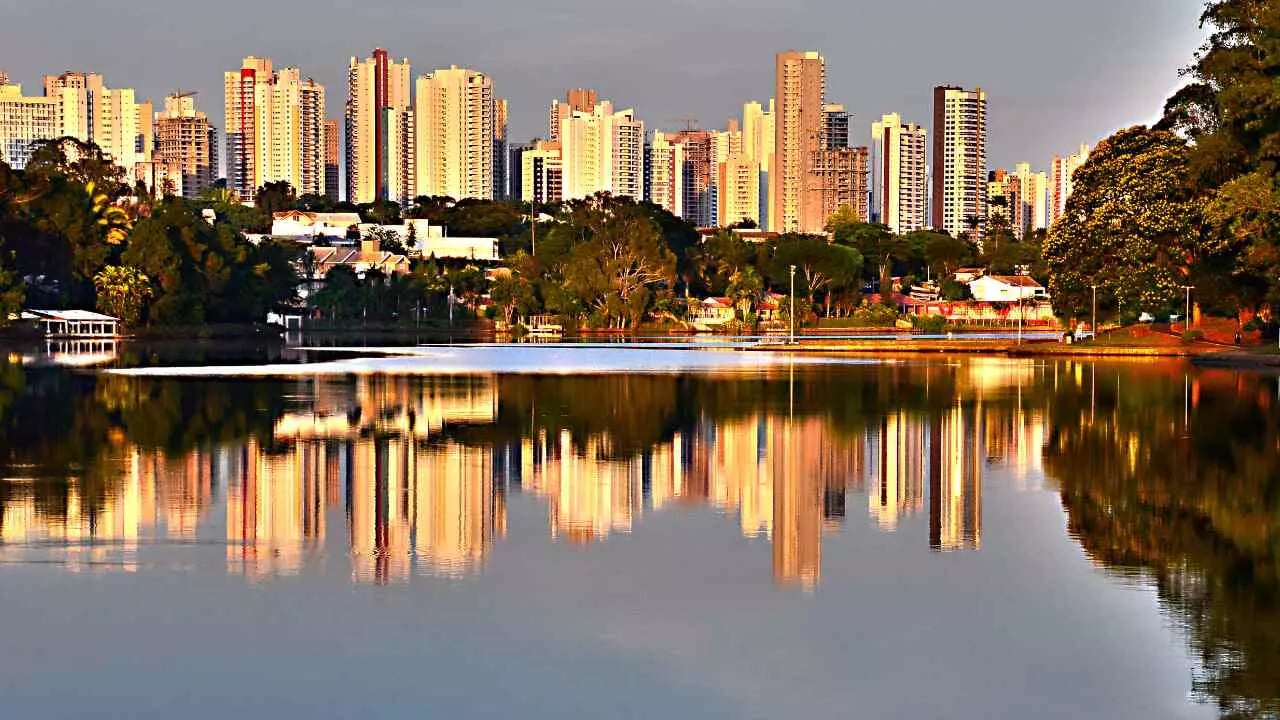 Londrina PR ao entardecer, com o Lago Igapó refletindo o skyline da cidade.