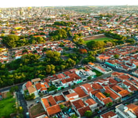 Vista aérea de Bauru SP ao entardecer, com prédios e áreas verdes.