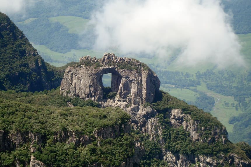 Paisagem montanhosa da Serra Catarinense, com formações rochosas e vegetação abundante sob céu parcialmente nublado.