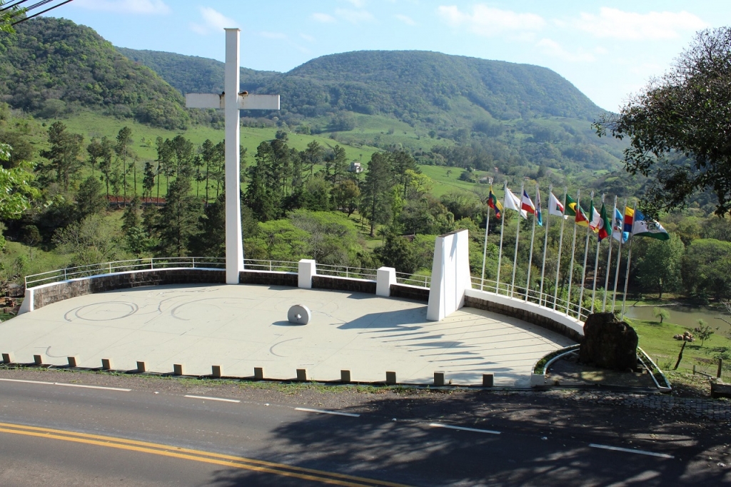 Paisagem de colinas verdes e monumento regional da Quarta Colônia