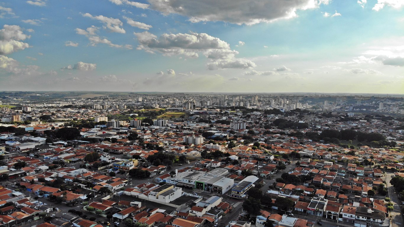 Vista aérea de Lins SP, com prédios baixos, áreas verdes e céu azul