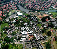 Vista aérea do campus da Unicamp em Campinas com prédios e áreas verdes ao entardecer