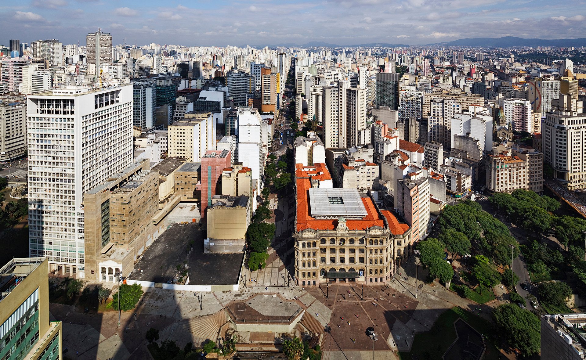 Vista urbana de São Paulo em um dia ensolarado, com prédios e um centro cultural ao fundo
