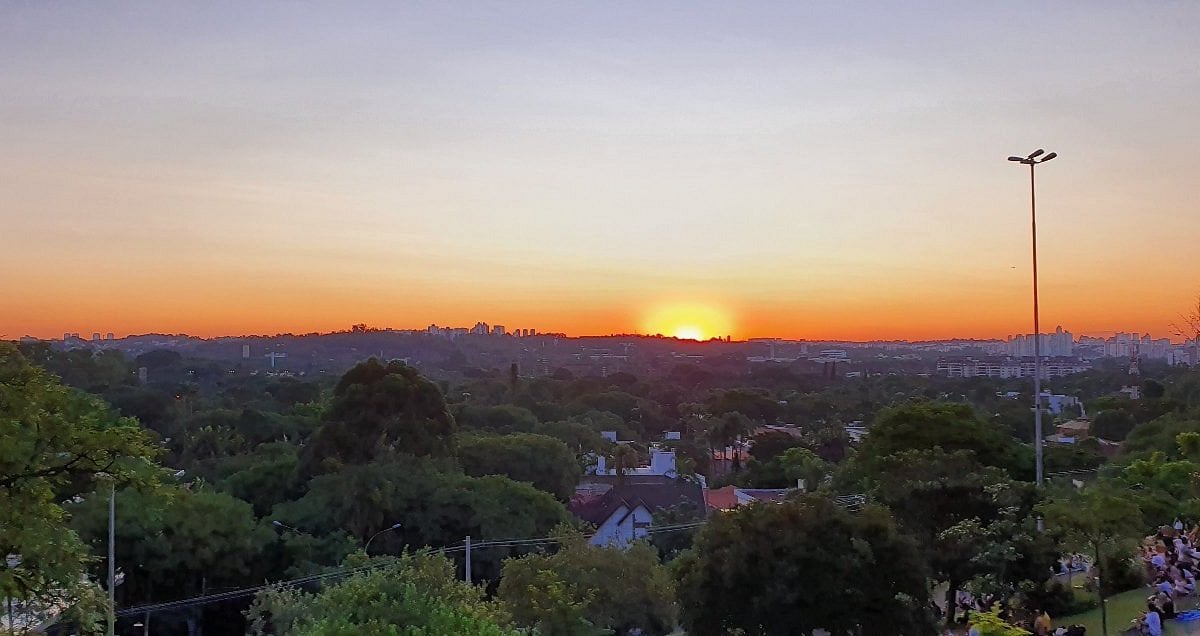 Pôr do sol em cidade do interior do Piauí, com árvores e céu alaranjado