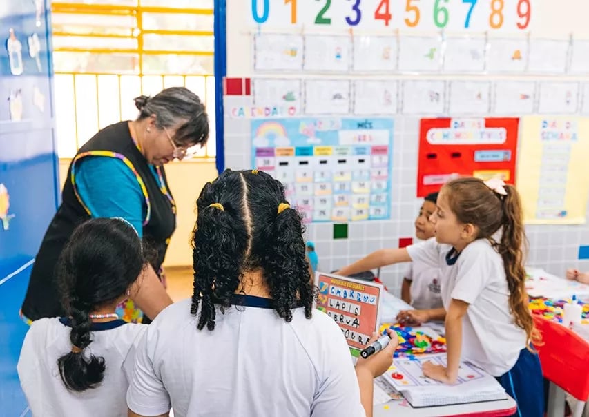 Sala de aula em escola pública, com alunos e professora em atividade