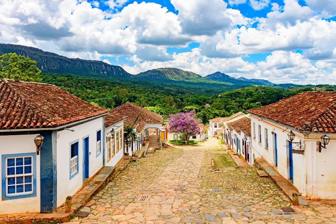 Paisagem urbana de cidade do interior de Minas Gerais, com casario e morros ao fundo.