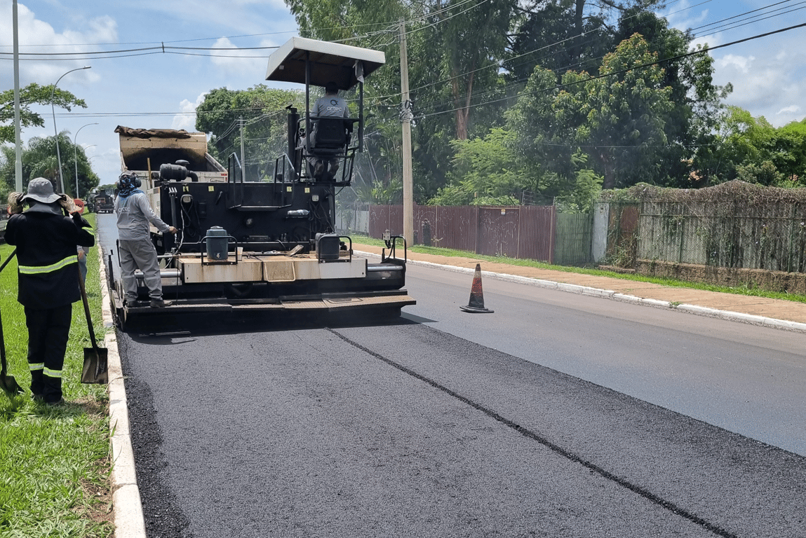 Equipe de obras em manutenção de via urbana, com equipamentos e cones de segurança