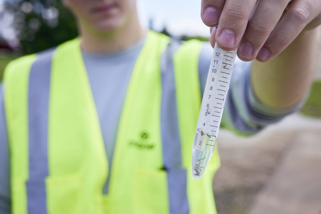 Agente de controle de vetores em atividade de campo, com EPI leve e prancheta