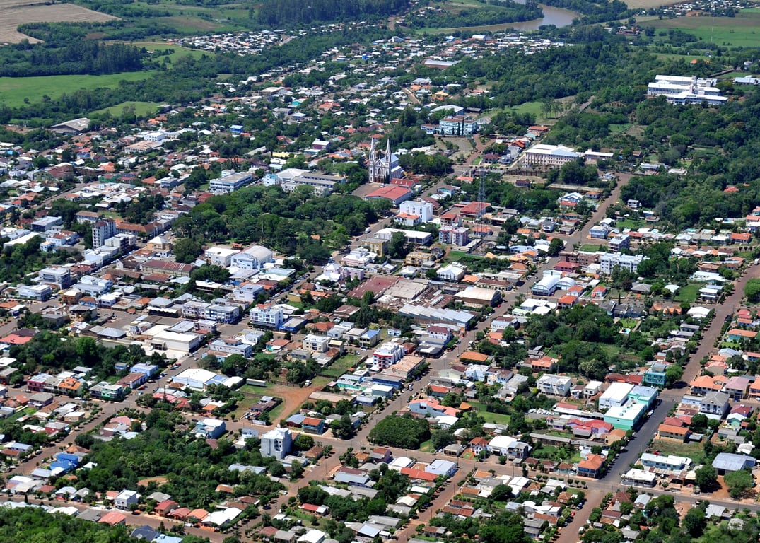 Vista aérea de Cerro Largo, com a malha urbana e áreas verdes ao fundo, em uma imagem horizontal ampla.