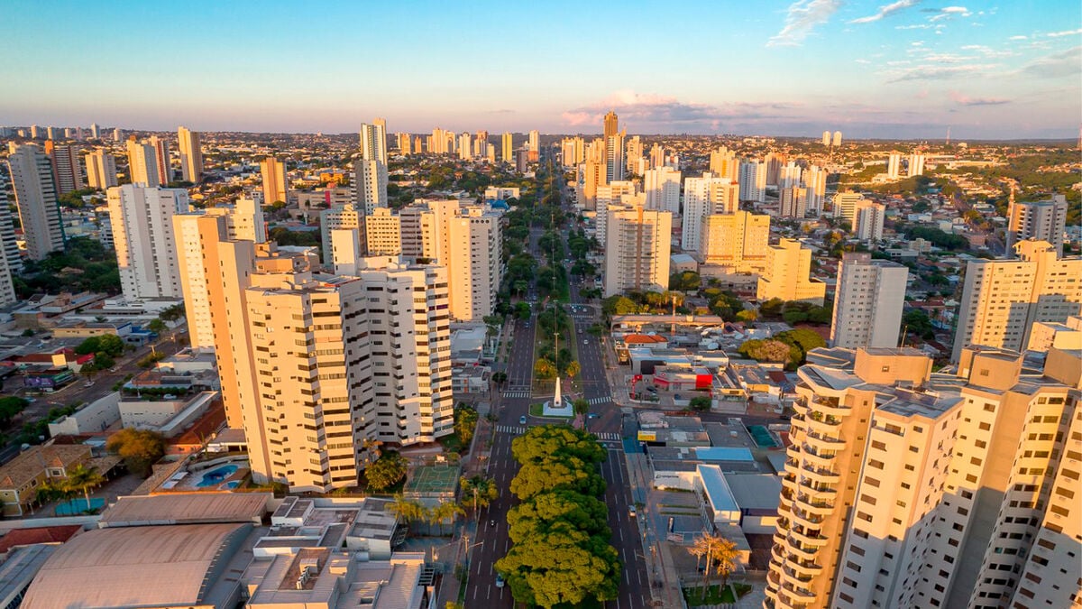 Vista aérea de Campo Grande ao entardecer, com áreas verdes e prédios