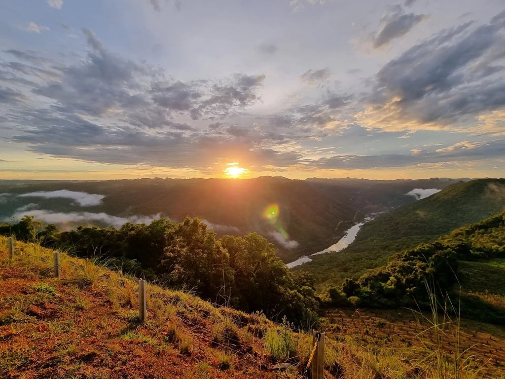 Vista panorâmica de Três Coroas, com morros da Serra Gaúcha e o Rio Paranhana ao entardecer