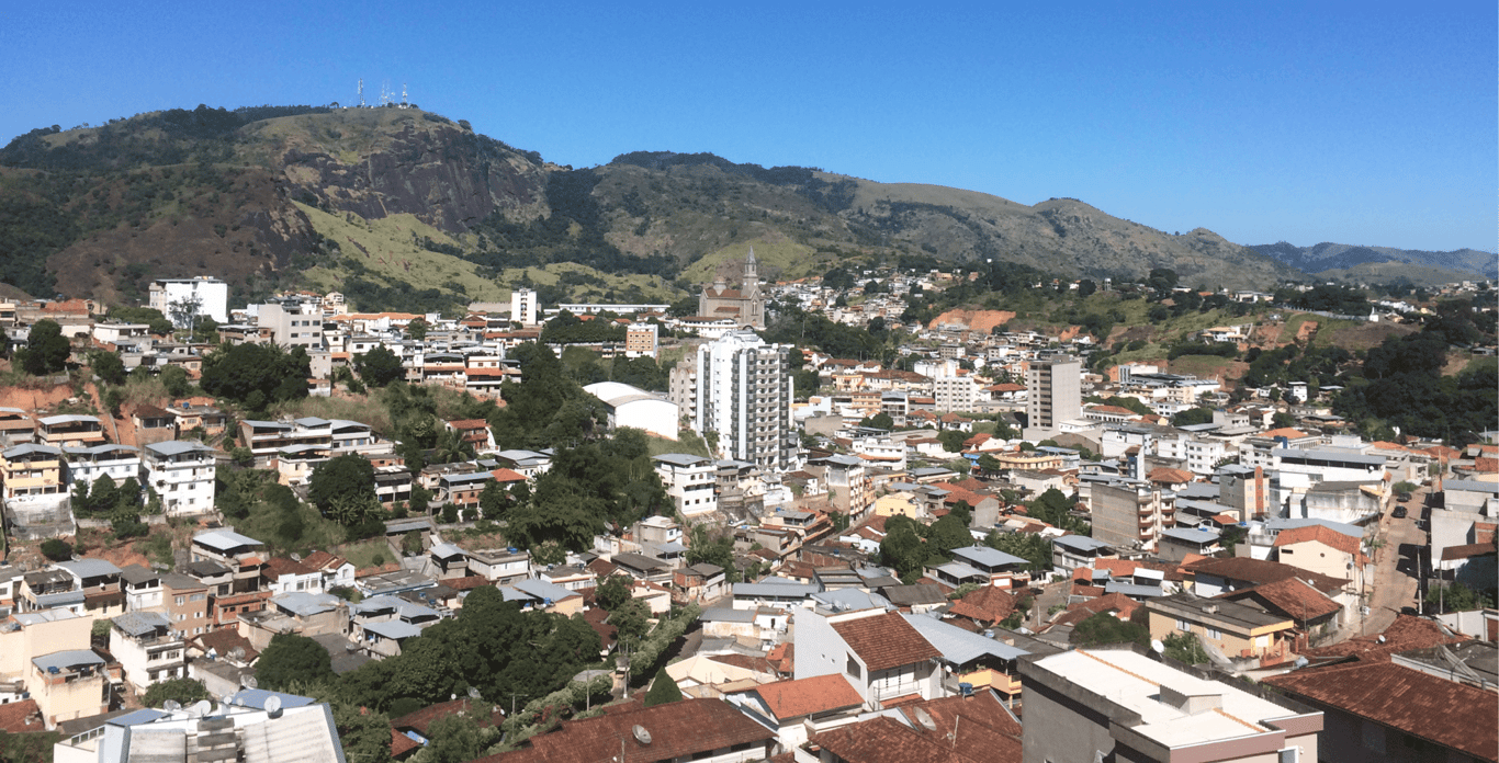 Vista aérea de Leopoldina (MG), com área urbana cercada por morros em dia de céu claro