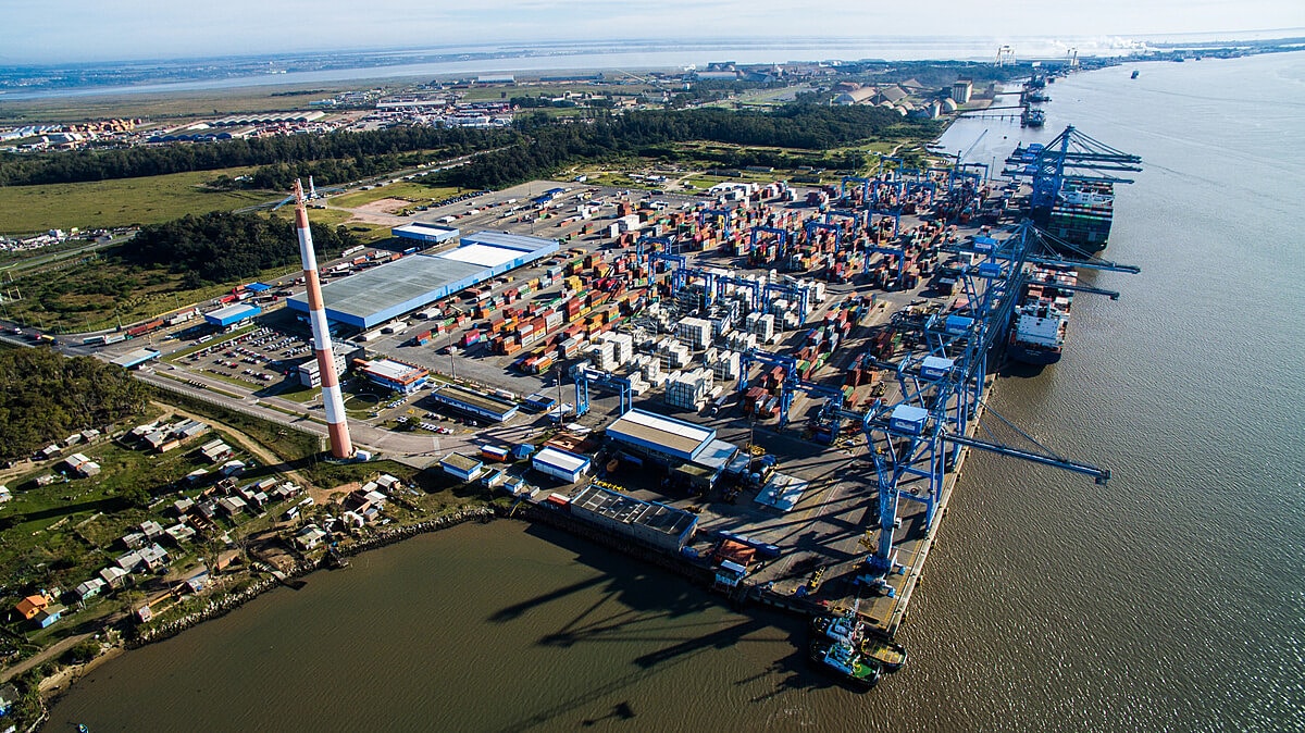 Vista aérea do Porto do Rio Grande ao entardecer, com pátios de contêineres e guindastes
