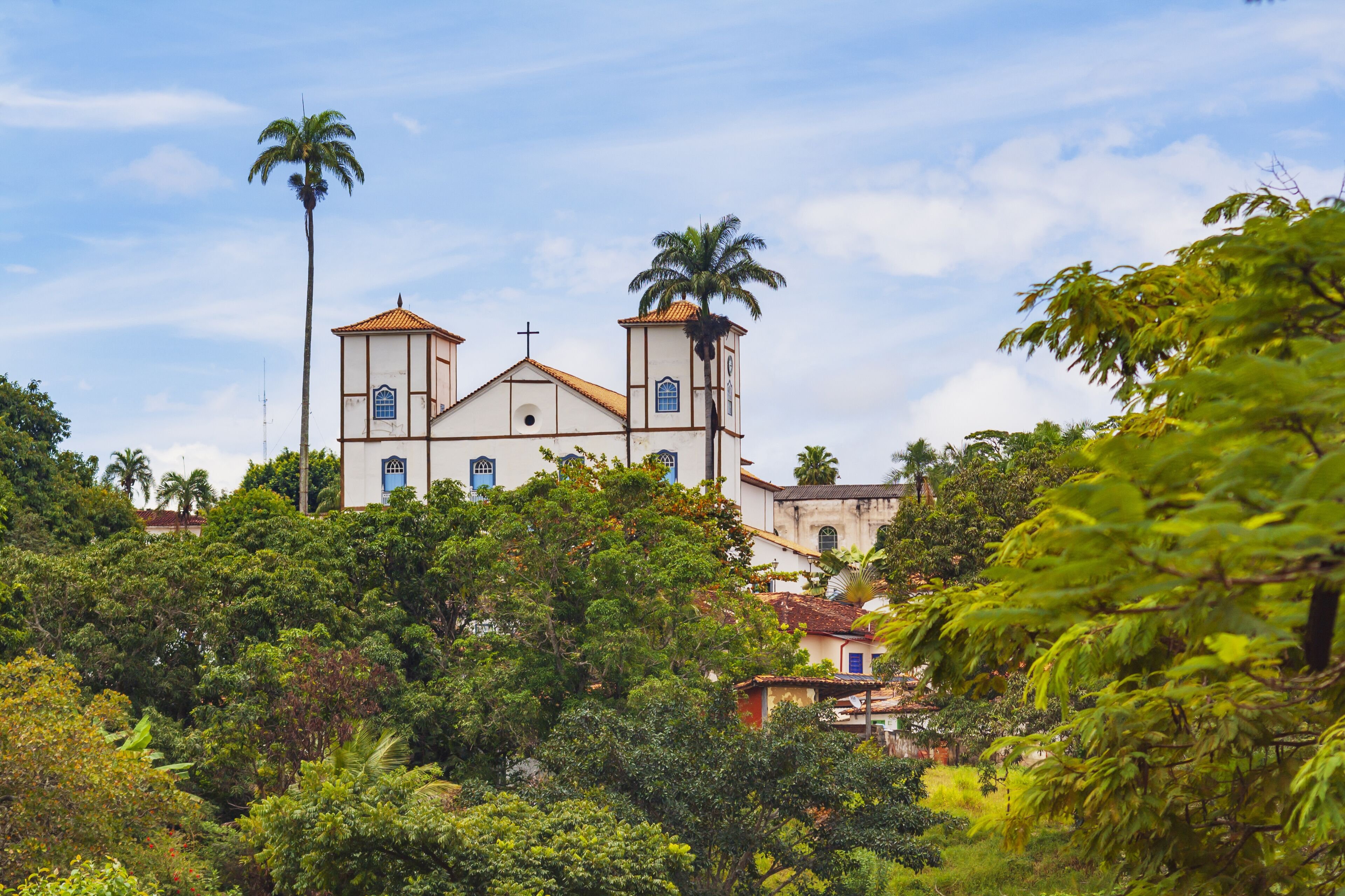 Vista urbana de Mambaí GO ao entardecer, com igreja e morros do Cerrado ao fundo