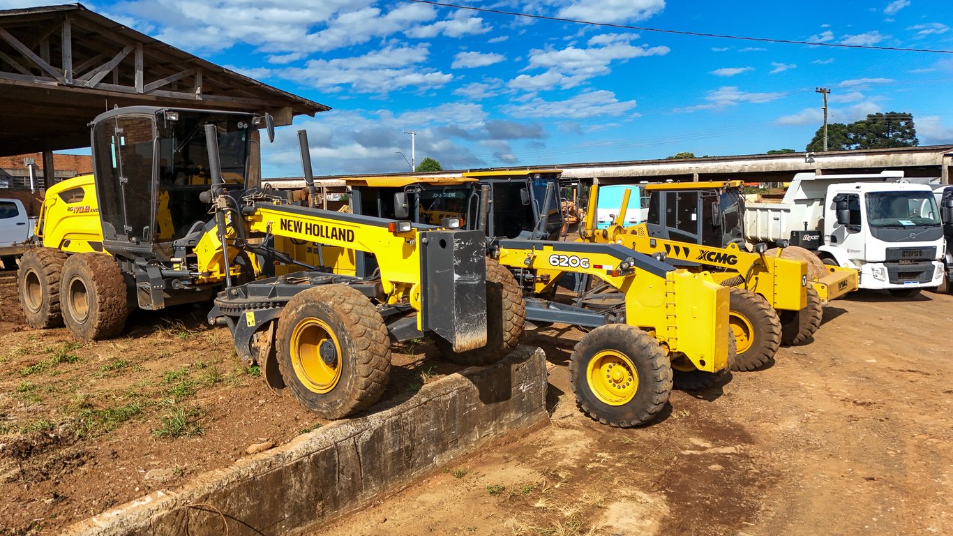 Máquinas de obras públicas em ação em via municipal, com operadores e EPIs