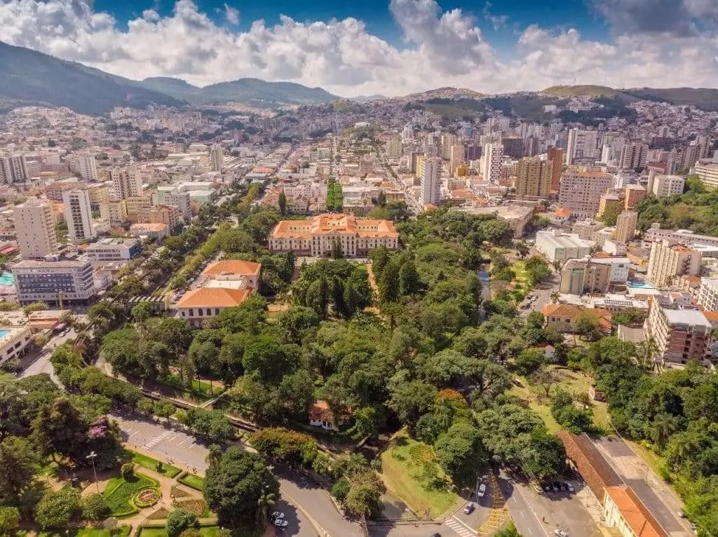 Vista urbana de cidade da Zona da Mata, com ruas arborizadas e montanhas ao fundo