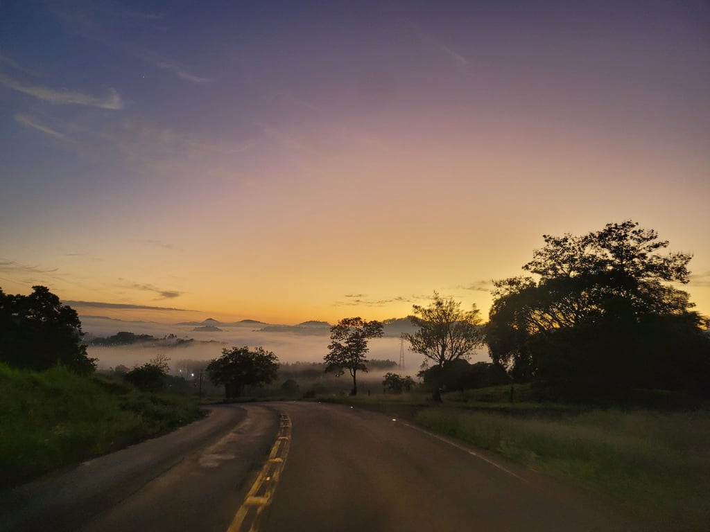 Paisagem urbana no Oeste de Santa Catarina ao amanhecer, com estrada e árvores; imagem ilustrativa da região de Riqueza SC.