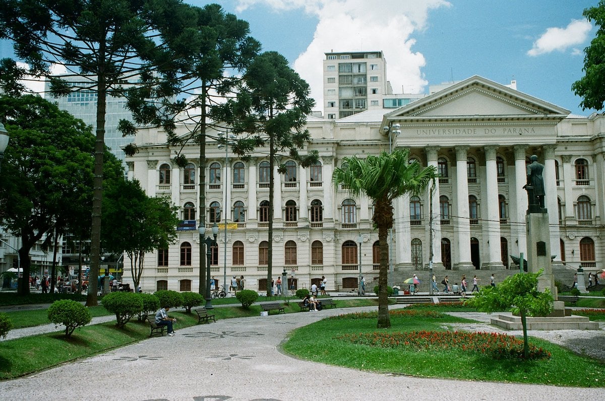 Ambiente universitário no Paraná, com jardins e pessoas circulando
