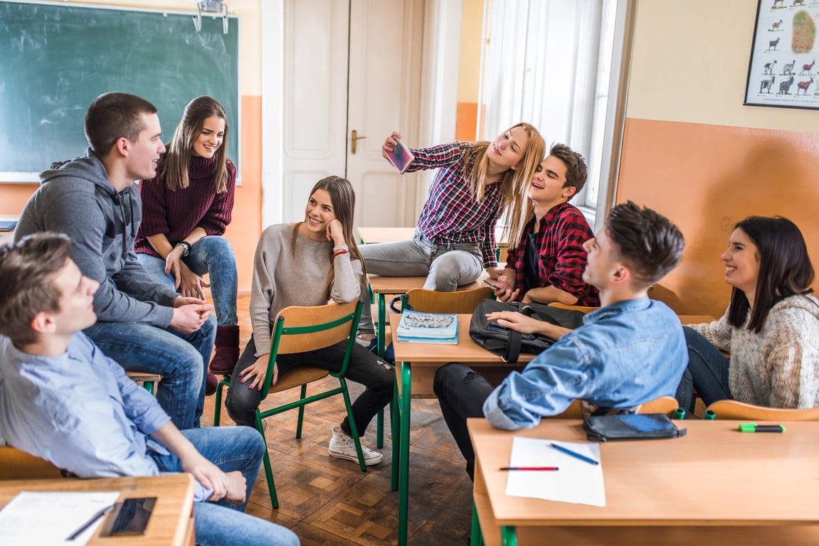 Professor em ambiente de ensino técnico, com gráficos no quadro e turma do ensino médio atenta