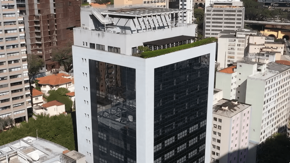 Prédio moderno de campus universitário em São Paulo, com vegetação no topo e entorno urbano