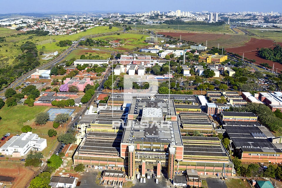 Vista aérea do campus da UNICAMP em Barão Geraldo, Campinas, com áreas verdes e prédios modernos