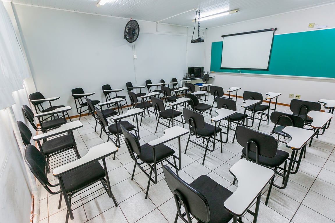 Sala de aula universitária com carteiras e lousa, imagem ilustrativa