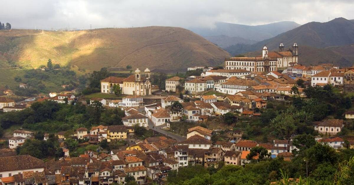 Centro histórico de cidade mineira com igreja e morros ao fundo