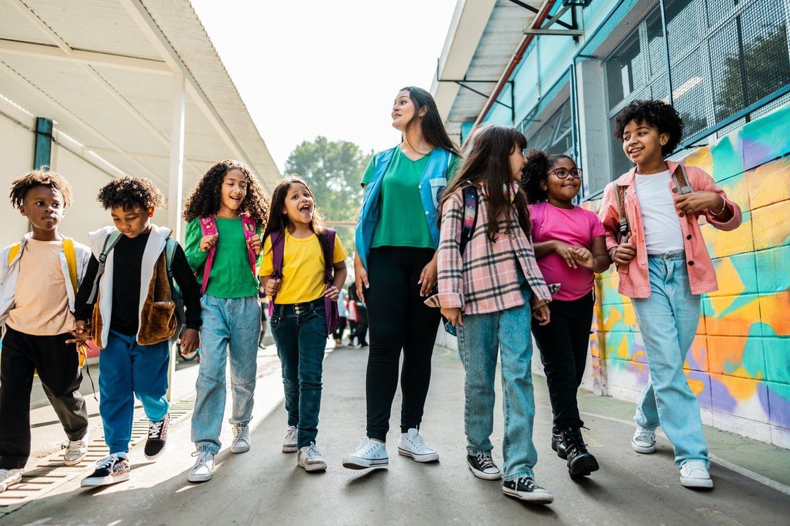 Ambiente escolar público no Brasil, com estudantes e professora caminhando pelo pátio colorido