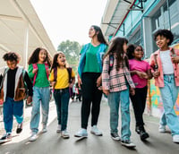 Estudantes e professora caminhando pelo pátio colorido de escola pública brasileira em Novo Repartimento PA