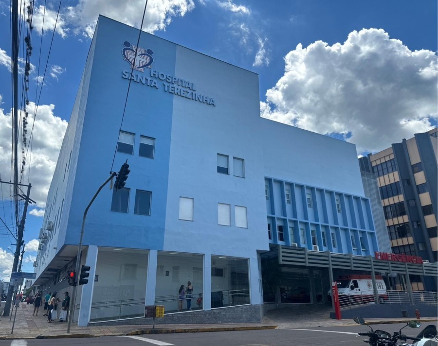 Fachada do Hospital Santa Terezinha, referência regional, com pessoas na área externa em dia de céu claro