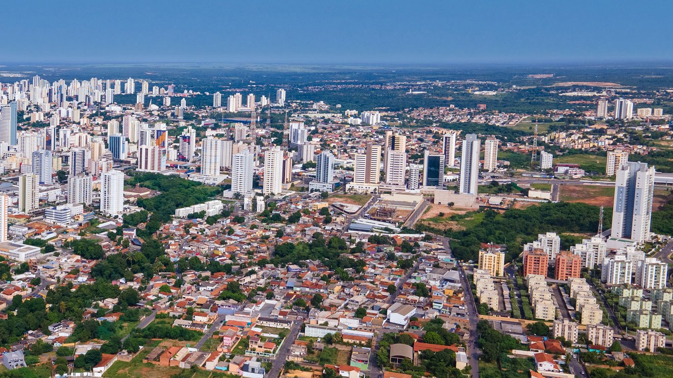 Skyline de Cuiabá em dia ensolarado, com prédios e áreas verdes