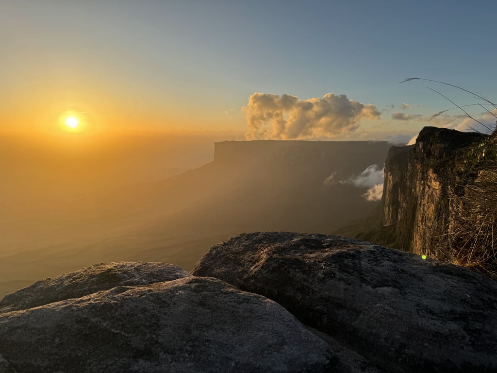 Paisagem de Roraima ao entardecer, com pedras em primeiro plano e serras ao fundo