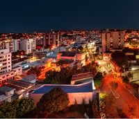 Vista urbana de Igrejinha à noite, com morros ao fundo e prédios iluminados