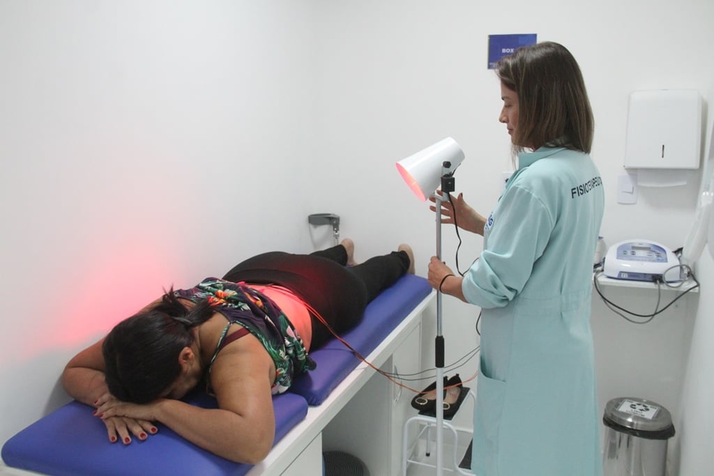 Atendimento de fisioterapia em ambiente de saúde, com profissional do SUS prestando cuidado a paciente