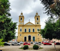 Vista urbana de Novo Cabrais RS, com igreja, carros e árvores ao redor.