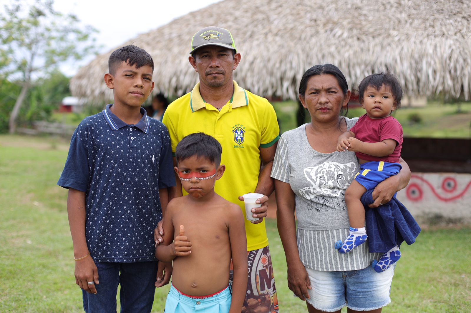 Profissional de assistência social em diálogo com família indígena em ambiente comunitário