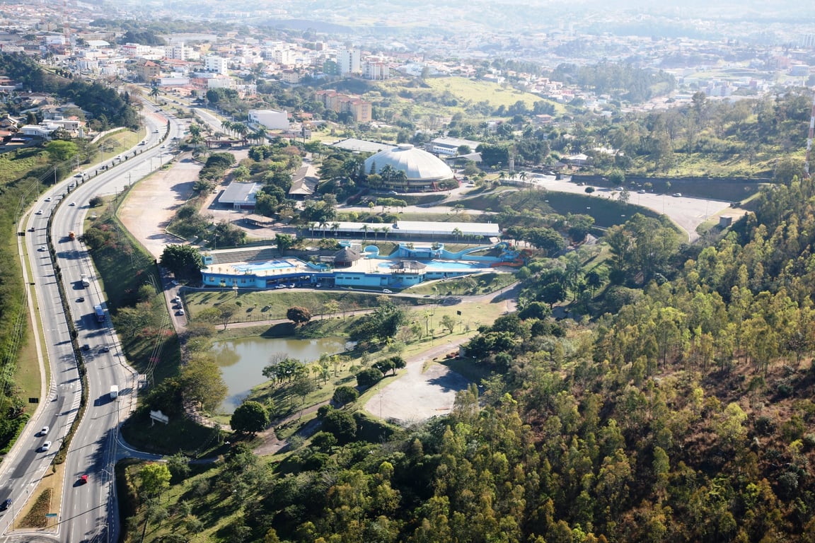 Vista aérea de Vinhedo ao pôr do sol, com áreas urbanas e verdes ao redor de um lago