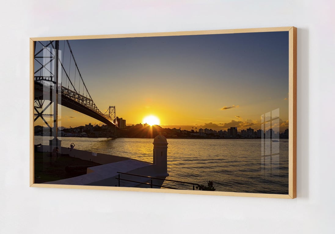 Ponte Hercílio Luz ao entardecer em Florianópolis, com skyline urbano e baía ao fundo