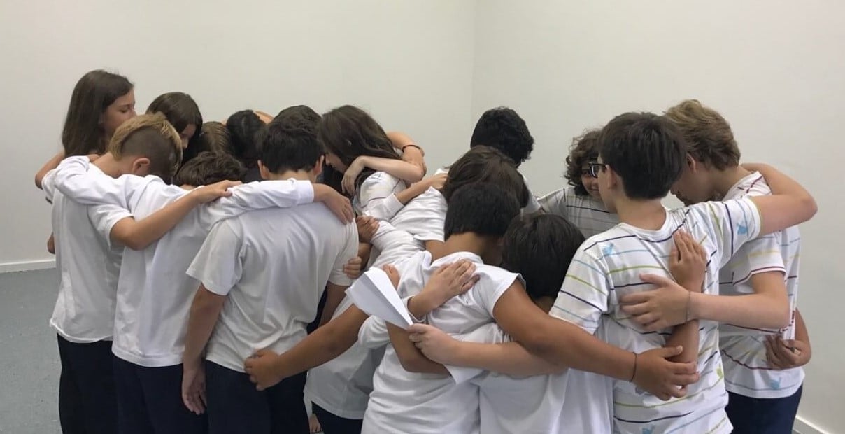 Alunos em dinâmica prática de teatro em sala de aula, atividade colaborativa