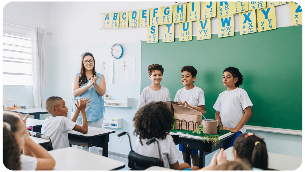 Professora em sala de aula, com estudantes do Ensino Fundamental participando de atividade em grupo