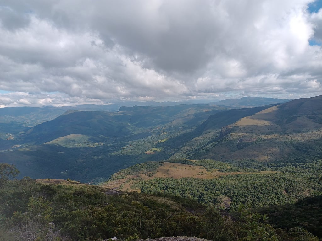 Paisagem rural em Minas Gerais, com morros verdes e céu nublado, simbolizando cidades do interior mineiro