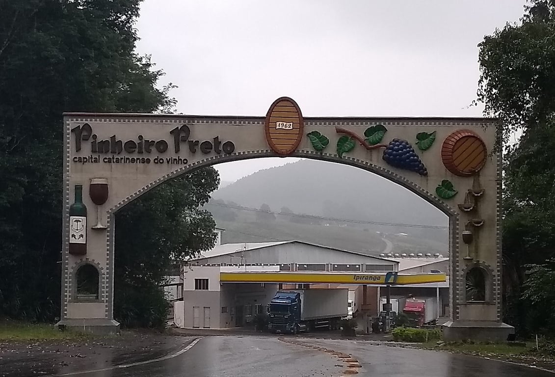 Arco de entrada de Pinheiro Preto com temática do vinho, estrada e áreas verdes ao fundo