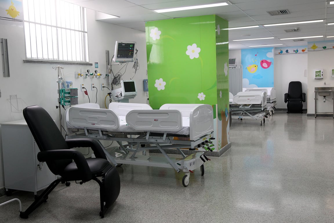 Ambiente hospitalar moderno com leitos e equipamentos, ilustrando área da Saúde