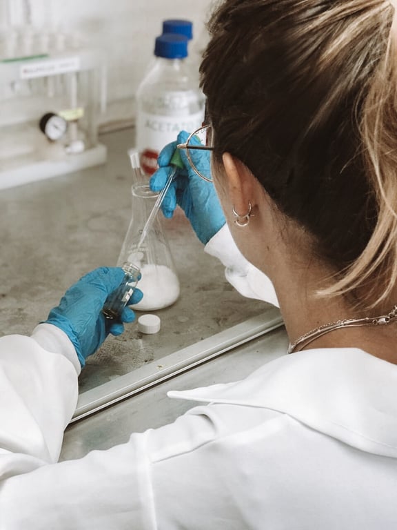 Laboratório acadêmico de farmacognosia, com pesquisadora manipulando vidrarias e amostras vegetais.