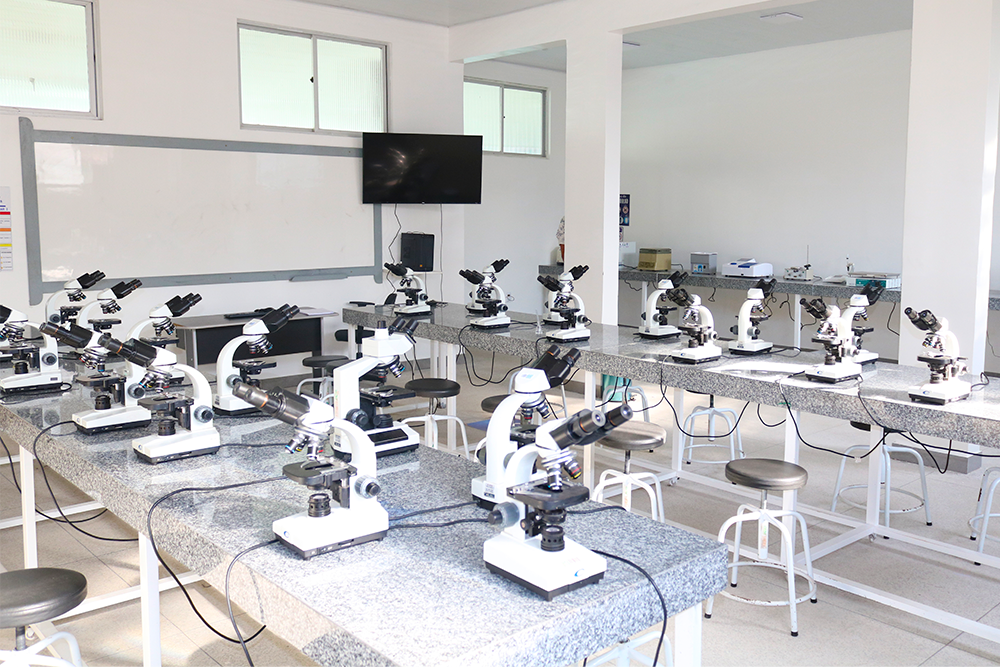 Laboratório de química universitário moderno, com microscópios e bancadas; ambiente institucional em perspectiva horizontal