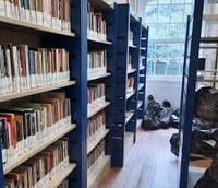 Biblioteca universitária da Unicamp com prateleiras de livros e luz natural.