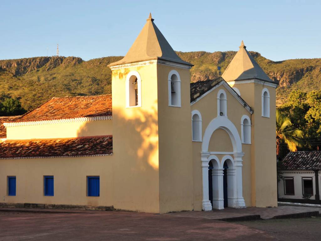 Igreja e praça de cidade do interior com montanhas ao fundo