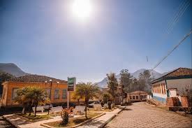Centro de cidade mineira, com igreja e praça vistos em perspectiva horizontal ampla