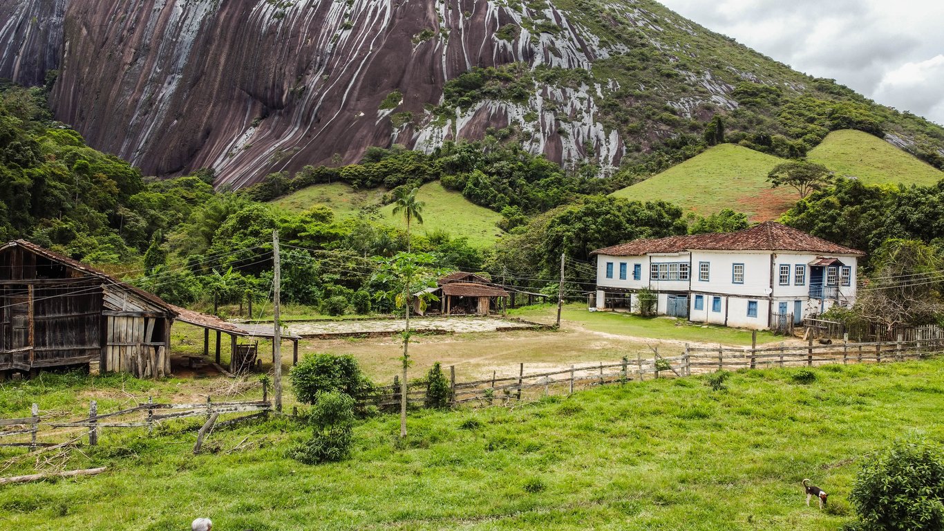 Paisagem rural do interior capixaba, com propriedades agrícolas e serras ao fundo
