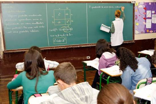 Sala de aula na rede pública, com professora e alunos em atividade